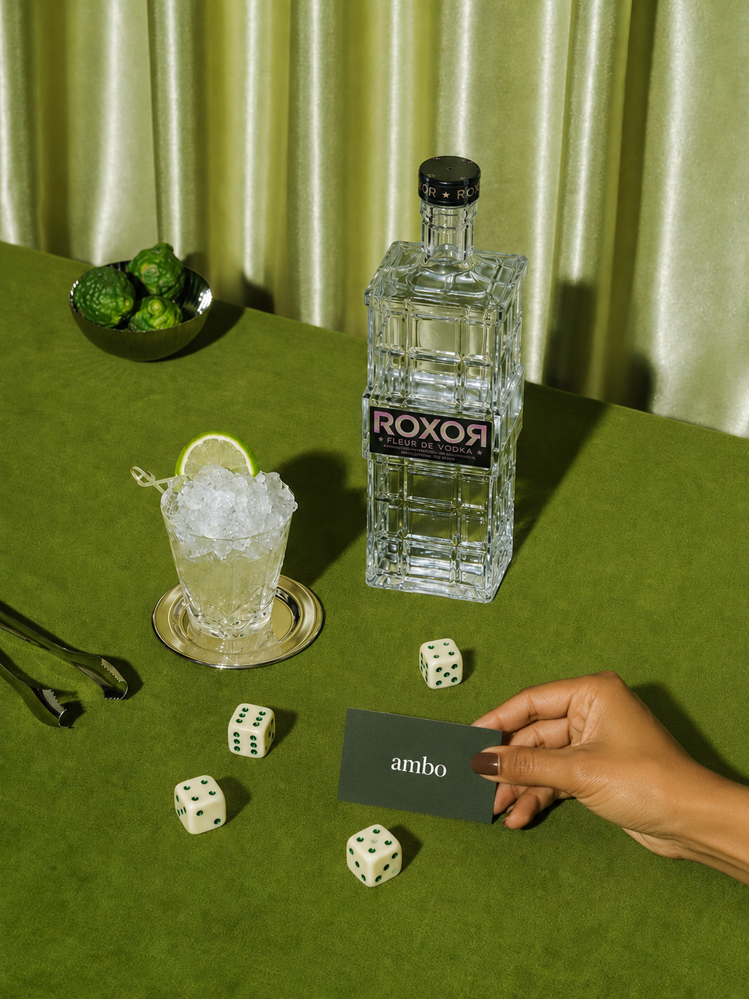 Ambo card with vodka, dice, and a cocktail on a green velvet table